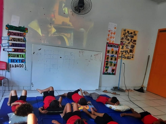 Alunos assistem um filme deitados na escola de Vila Restauração