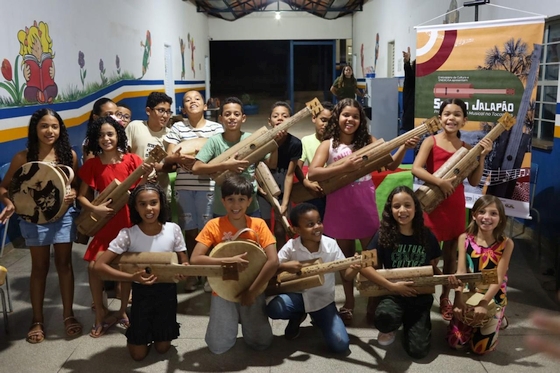 Crianças com instrumentos na mão durante aula do projeto