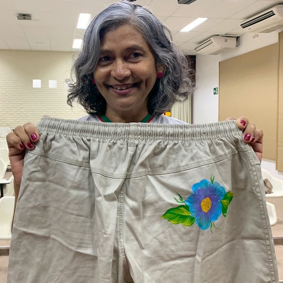 Mulher segura calça com uma flor pintada à mão